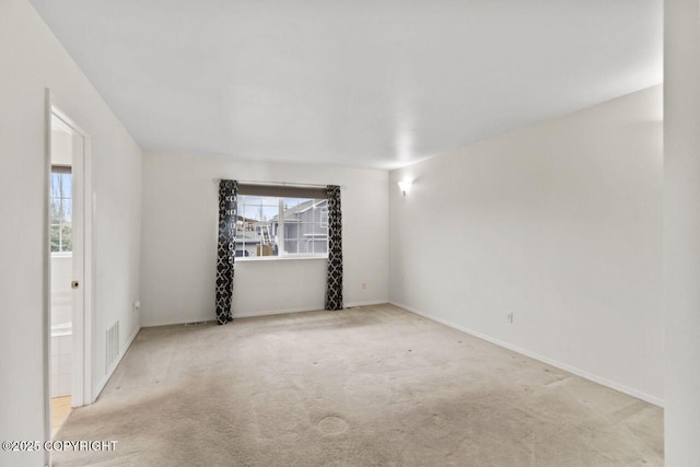 empty room featuring carpet flooring, visible vents, and baseboards