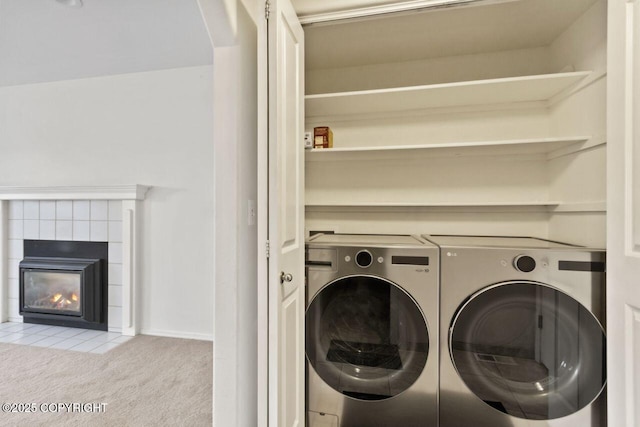 clothes washing area with carpet floors, laundry area, a fireplace, and washing machine and clothes dryer