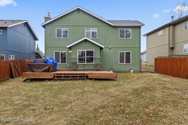 back of property with a fenced backyard, a lawn, and a deck