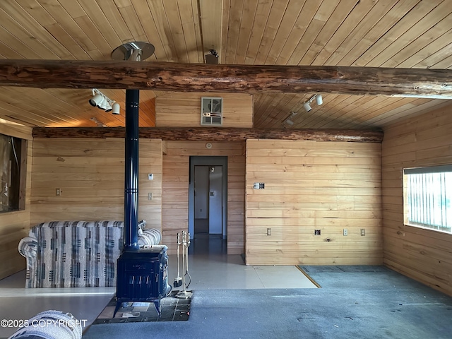 interior space with wood ceiling, wood walls, beamed ceiling, and a wood stove