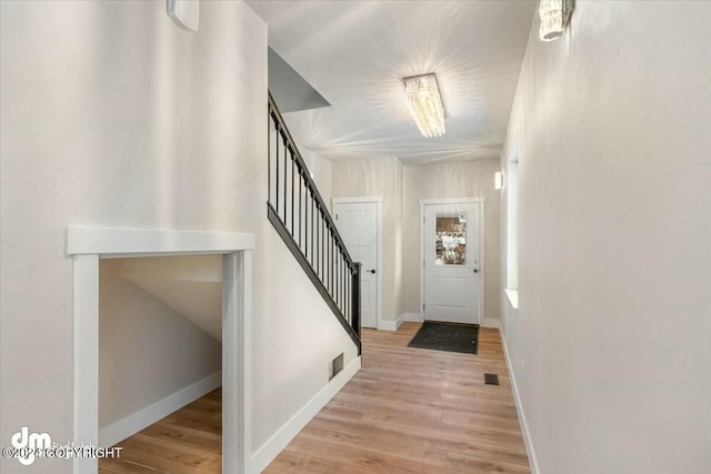 foyer featuring light wood-style flooring, visible vents, stairway, and baseboards