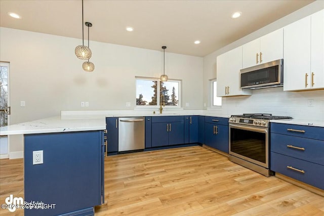 kitchen with stainless steel appliances, blue cabinetry, a peninsula, and light wood-style flooring