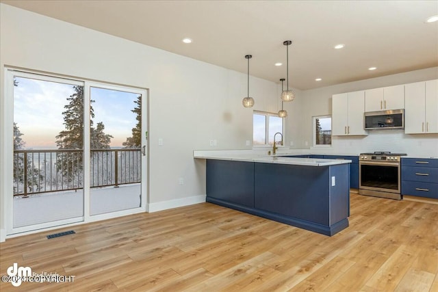 kitchen with light countertops, visible vents, appliances with stainless steel finishes, white cabinetry, and a peninsula