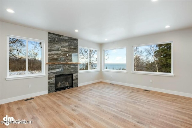 unfurnished living room featuring recessed lighting, a fireplace, wood finished floors, visible vents, and baseboards