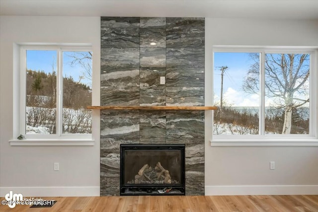 unfurnished living room featuring a fireplace, wood finished floors, and baseboards