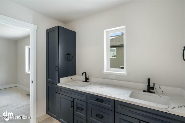 bathroom with double vanity, baseboards, and a sink