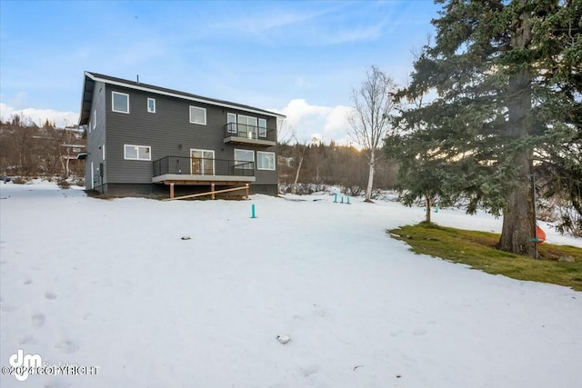 snow covered back of property featuring a balcony