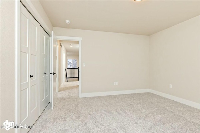 unfurnished bedroom with baseboards, a closet, and light colored carpet