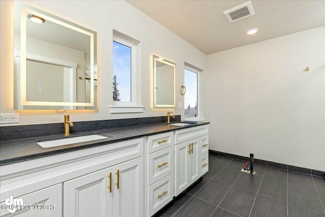 bathroom featuring tile patterned floors, visible vents, a sink, and double vanity