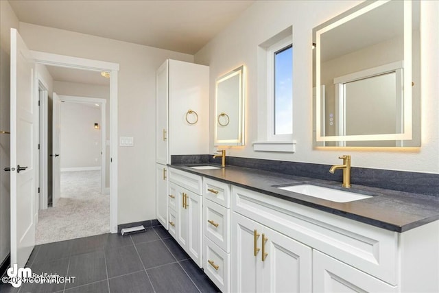 full bathroom featuring double vanity, tile patterned flooring, a sink, and baseboards