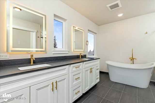 bathroom with double vanity, visible vents, a sink, and tile patterned floors