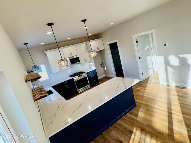 kitchen with light stone countertops, decorative light fixtures, and light wood-style floors