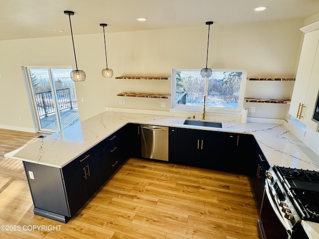 kitchen featuring dark cabinetry, light wood-style floors, a peninsula, and appliances with stainless steel finishes