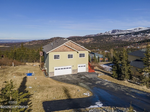 exterior space featuring a mountain view, an attached garage, driveway, and stone siding