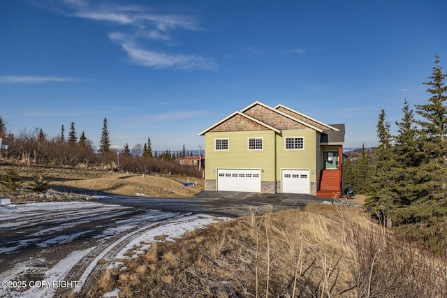 view of side of property with an attached garage, stone siding, and driveway