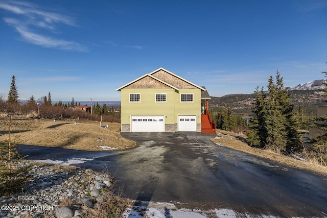 view of side of home with stone siding, driveway, and a garage