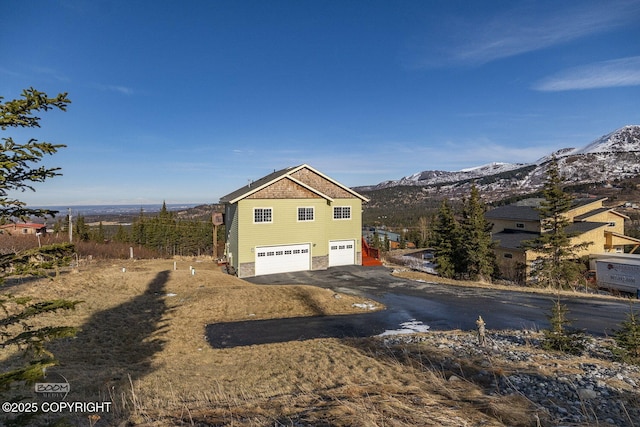 view of side of home with aphalt driveway, an attached garage, and a mountain view