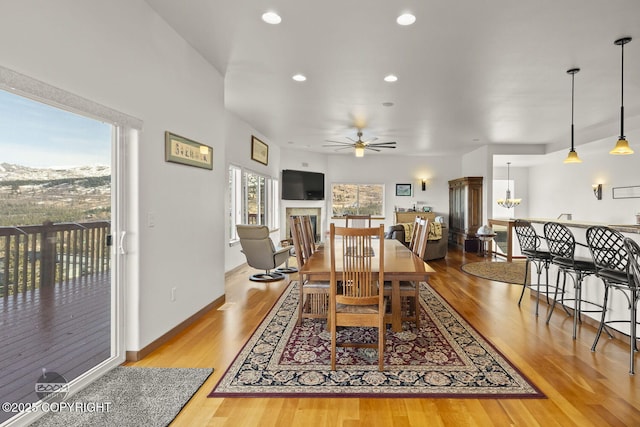 dining area with wood finished floors, recessed lighting, a fireplace, baseboards, and ceiling fan