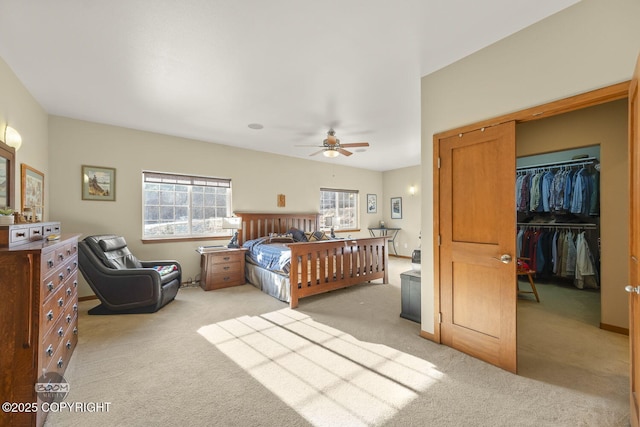 bedroom with light carpet, a spacious closet, a ceiling fan, and a closet