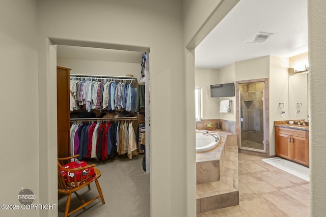 full bathroom featuring vanity, visible vents, a stall shower, a spacious closet, and a garden tub