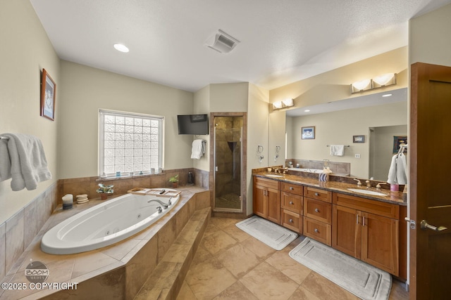 bathroom featuring a sink, a tub with jets, a shower stall, and double vanity