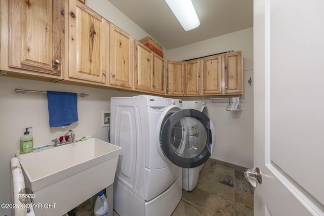 laundry room featuring a sink, baseboards, cabinet space, and washing machine and clothes dryer