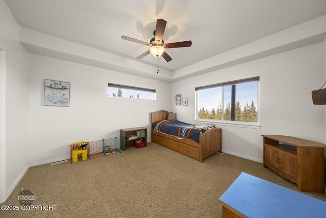 carpeted bedroom featuring a raised ceiling, baseboards, and ceiling fan