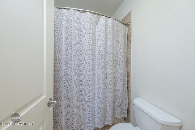 bathroom featuring a shower with shower curtain and toilet