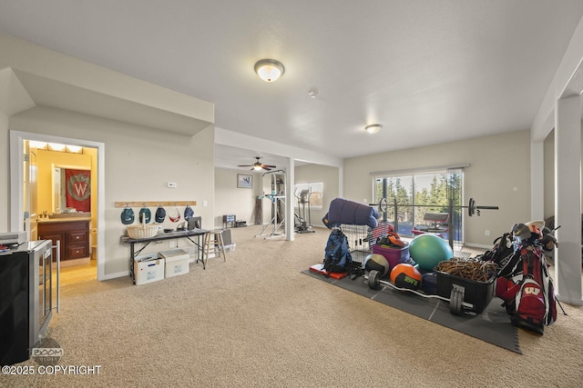 exercise room featuring light colored carpet, baseboards, and a ceiling fan