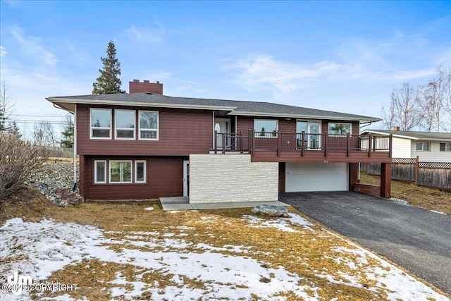 view of front facade featuring fence, driveway, an attached garage, a chimney, and stone siding