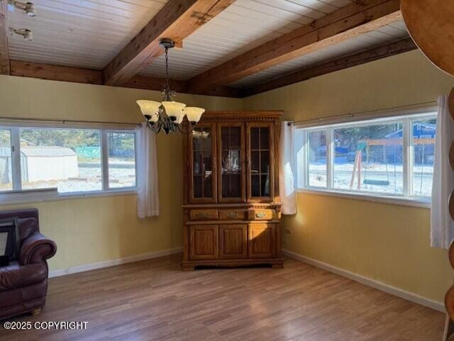 dining space featuring light wood-type flooring, baseboards, a chandelier, and beamed ceiling