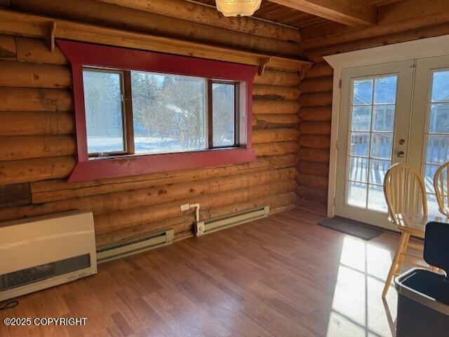 interior space with a baseboard radiator, beamed ceiling, wood finished floors, and french doors