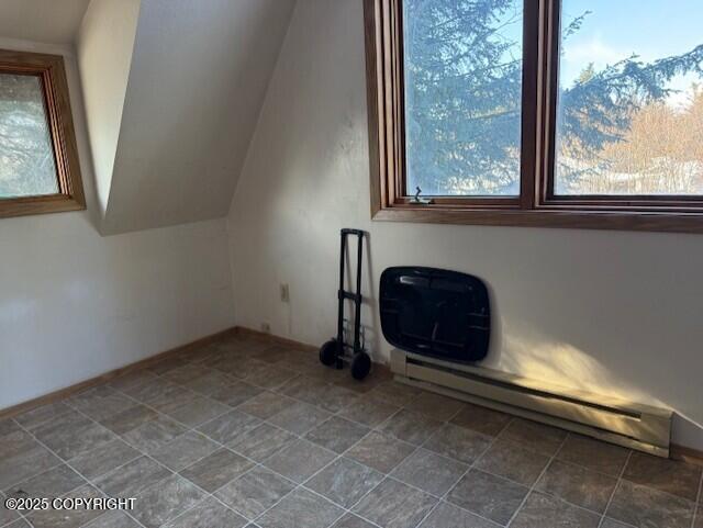 additional living space featuring plenty of natural light, a baseboard heating unit, and vaulted ceiling