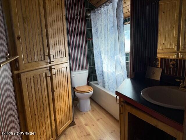 bathroom featuring wood finished floors, vanity, toilet, and shower / tub combo with curtain