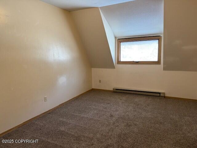 additional living space featuring carpet, a baseboard heating unit, vaulted ceiling, and baseboards