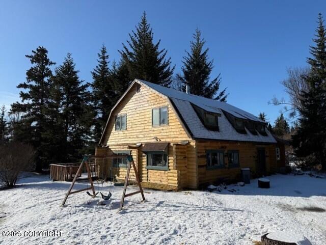 snow covered property with a playground and a gambrel roof