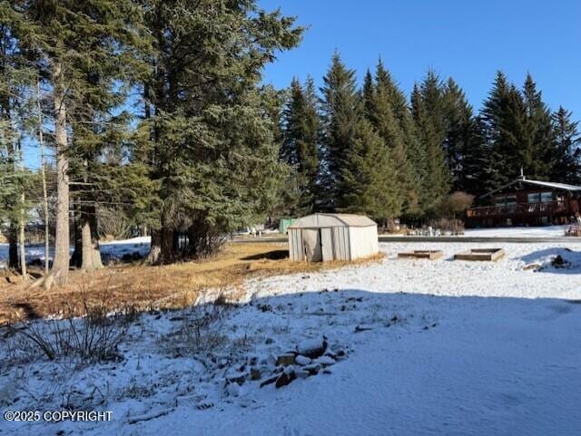 snowy yard featuring an outdoor structure and a storage unit