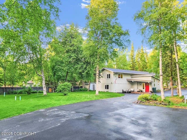 view of side of property with aphalt driveway, fence, and a yard