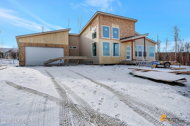 snow covered rear of property with a garage