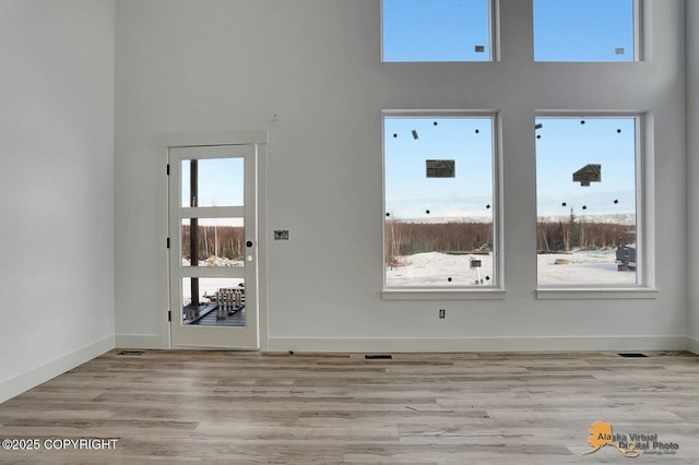 interior space with baseboards, a high ceiling, and light wood finished floors