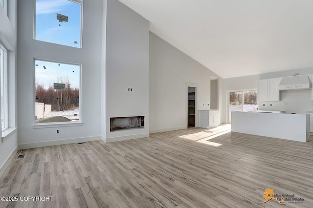 unfurnished living room with light wood-style flooring, a fireplace, and visible vents