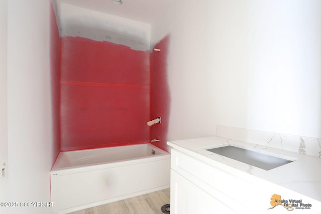 full bathroom featuring wood finished floors, a sink, and a bathing tub