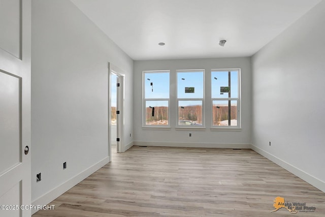 empty room with light wood finished floors and baseboards