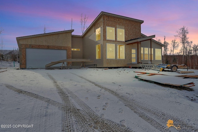 back of house at dusk featuring an attached garage