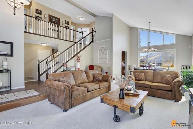 carpeted living area with stairs, visible vents, a towering ceiling, and an inviting chandelier