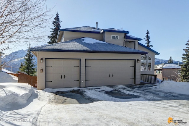 exterior space featuring an attached garage, a shingled roof, and fence