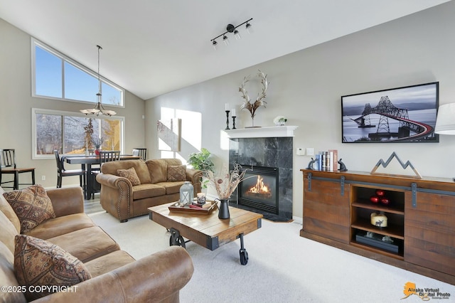 living room featuring a chandelier, high vaulted ceiling, carpet flooring, a tiled fireplace, and track lighting