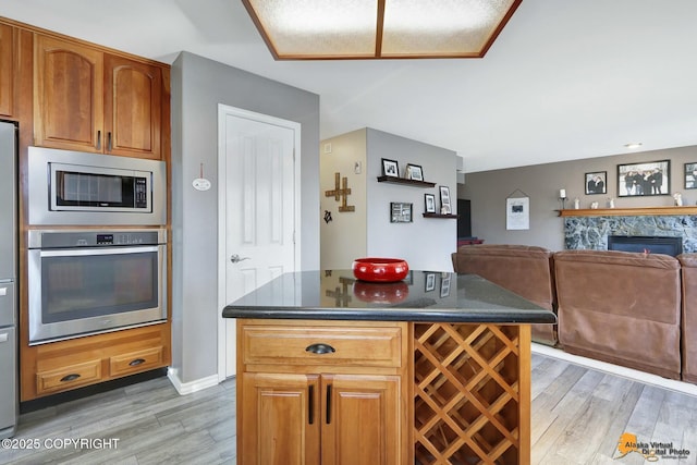 20420 Williamsburg Dr, Eagle River, AK 99577 - kitchen featuring stainless steel appliances, light wood finished floors, open floor plan, a glass covered fireplace, and a kitchen island