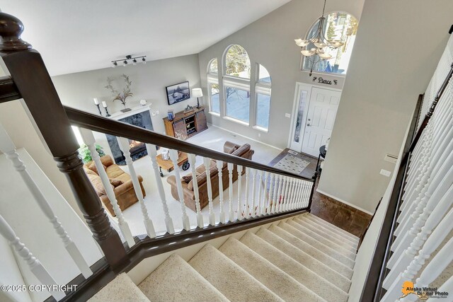 20420 Williamsburg Dr, Eagle River, AK 99577 - stairs featuring baseboards, a chandelier, wood finished floors, and high vaulted ceiling