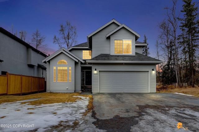 traditional home with aphalt driveway, fence, a shingled roof, and a garage